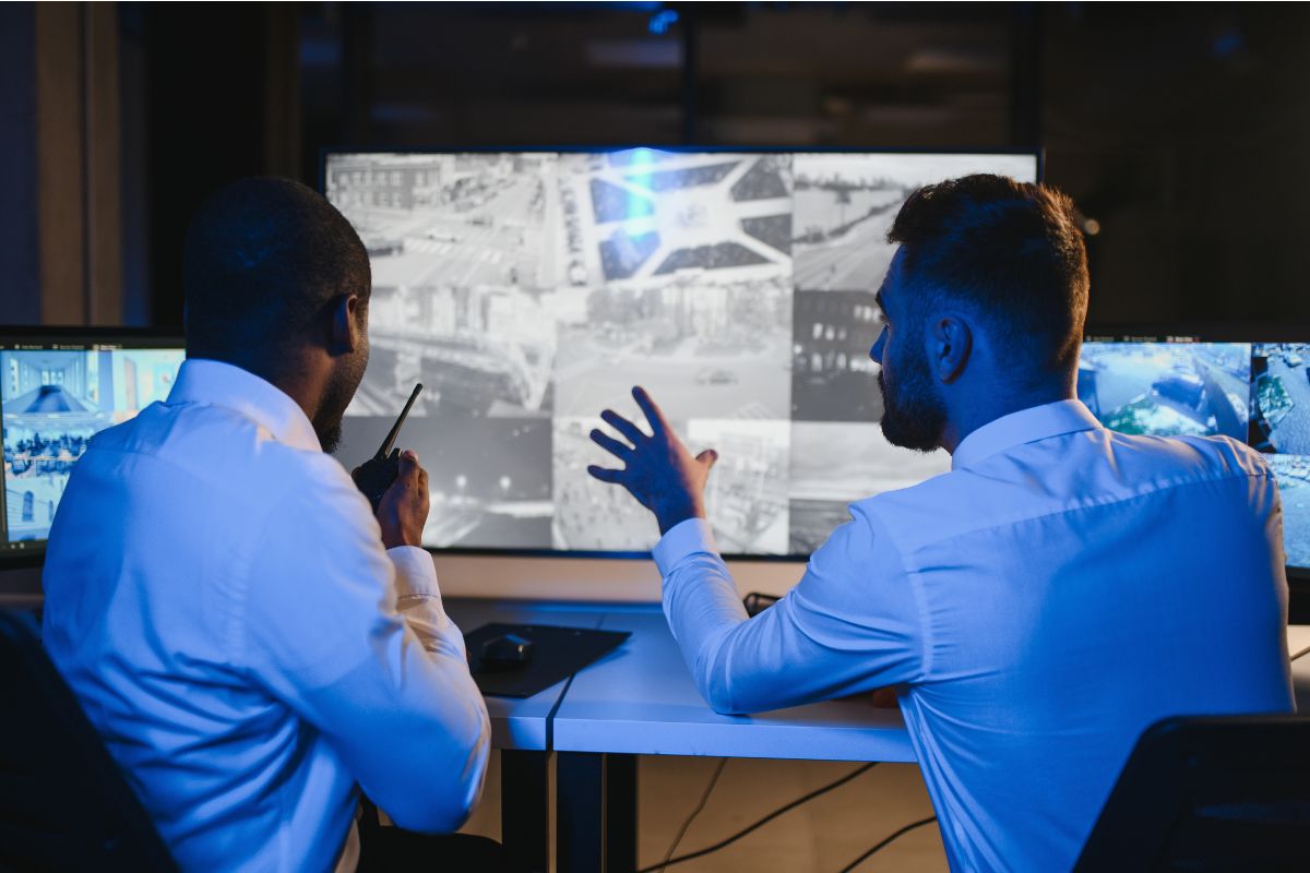 Security professionals collaborating at a monitoring station while reviewing surveillance cameras