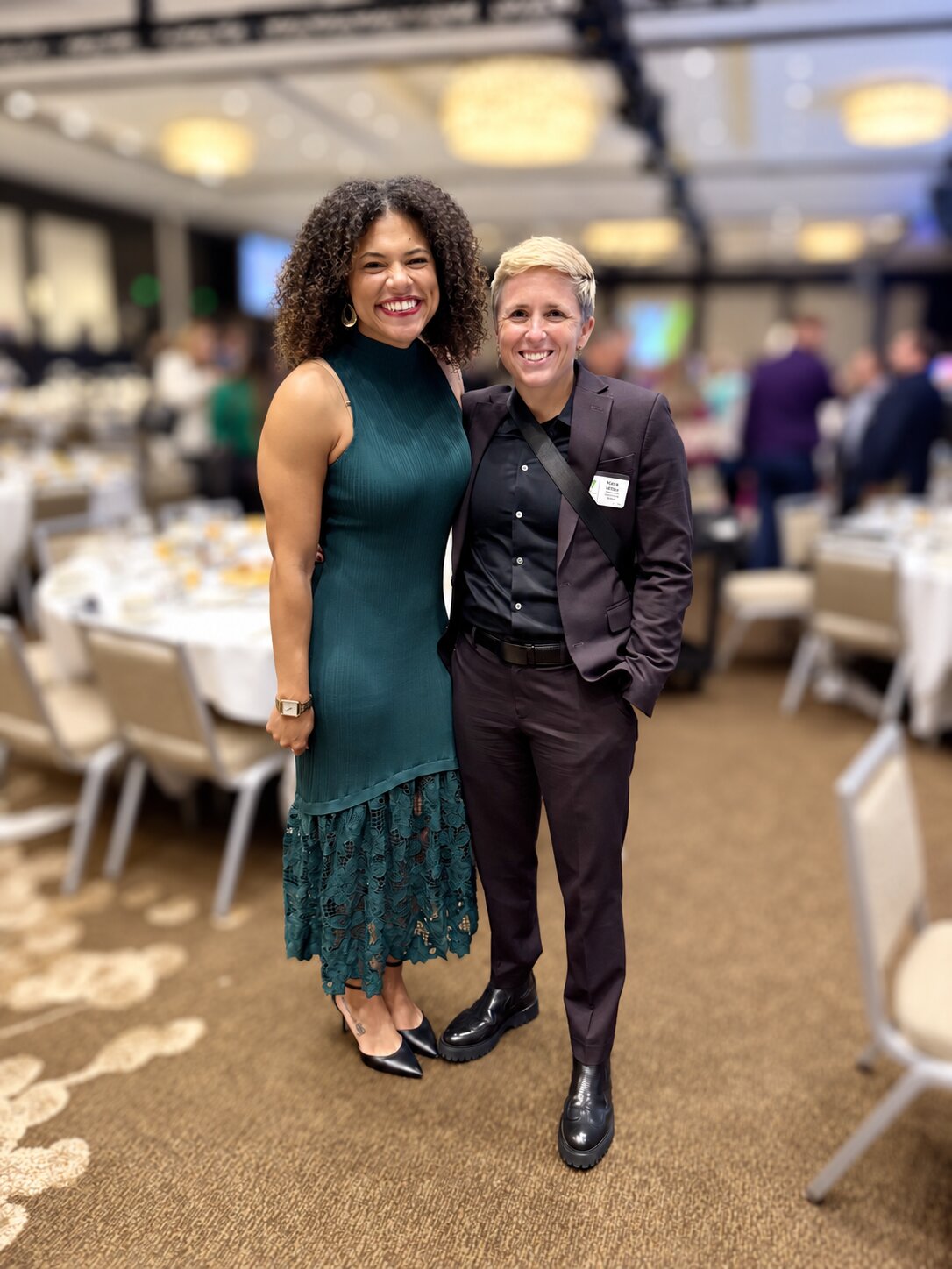 Two women smiling together at a banquet event